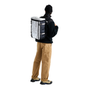 A person shown from the back wearing a black beanie, black fleece jacket, tan cargo pants, and hiking boots, while carrying a large insulated delivery backpack. The backpack is white and black with the text 'THE DELIVERY' visible on the side.