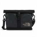The North Face black roll-top duffel bag with a silver logo on the front, featuring a black webbing strap closure and an adjustable shoulder strap with carabiners, shown against a plain white background.