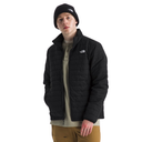 A man wearing a black puffer jacket by The North Face, styled with a black beanie, a beige henley shirt, and brown pants, set against a plain white background.