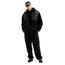 A model wearing a black hooded The North Face jacket with glossy black vinyl panels on the chest, black cargo pants, and black sunglasses, standing against a solid white background.