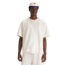 Person wearing a white textured t-shirt and pants with a cap on a white background