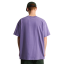 A man viewed from behind wearing an oversized lavender-purple t-shirt, a dark green baseball cap, and dark green pants, set against a plain white background.
