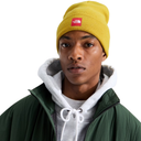 A close-up of a person wearing a mustard yellow beanie with a red The North Face logo, a dark green jacket, and a white hoodie, set against a plain white background.