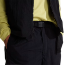 Person wearing a black vest over a yellow shirt with a visible brand logo.