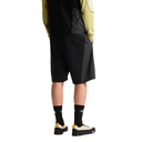 Person wearing black shorts and black shoes with a white background