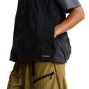 Person wearing a black jacket with 'WINDWALL' branding, green pants, and a checkered shirt on a white background.
