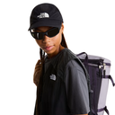 Person wearing The North Face cap, sunglasses, and carrying a backpack on a white background