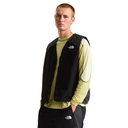 Person wearing a black vest over a light green shirt with The North Face logo.