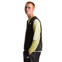Person wearing a black vest over a light green long-sleeve shirt on a white background