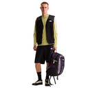 Man wearing a black vest and green shirt with a purple backpack on a white background