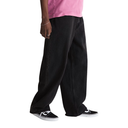 A person wearing very loose, wide-leg black jeans or pants with a pink shirt and black low-top sneakers, shown from the waist down on a plain white studio background.