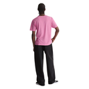 A person shown from the back wearing a light pink short-sleeve t-shirt and loose black jeans, standing against a plain white background.