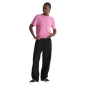 A model wearing a light pink short-sleeve crewneck t-shirt, black wide-leg jeans, a silver belt, and black sneakers, standing against a solid white background.