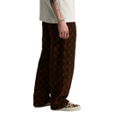 A person shown from the waist down wearing loose brown checkered pants, a light beige T-shirt, and leopard-print sneakers against a plain white background.