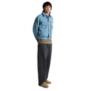 A model stands in profile wearing a light blue denim jacket over a tan shirt, dark charcoal gray wide-leg trousers, and tan shoes, against a plain white background.
