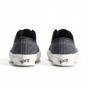A pair of Vans slip-on sneakers shown from the back, featuring a dark gray denim-textured canvas upper, black collar lining, and white rubber soles with the Vans logo.