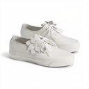 A pair of white low-top lace-up sneakers with decorative white flower embellishments on the sides, shown on a clean white background.