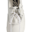 A close-up of a white leather Vans boat shoe featuring white laces, a decorative white leather accent piece on the side, and a black Vans logo visible inside the collar.