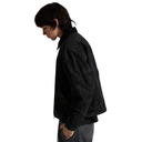 A person shown in side profile wearing a black textured jacket and dark gray jeans against a plain white background.