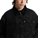 A close-up of a person wearing a black textured zip-up jacket with a collar, chest pocket, and silver snap details, photographed against a plain white background.