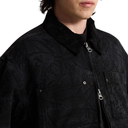 Close-up of a person wearing a black textured jacket with a collar, front zipper, and chest pockets against a plain white background.