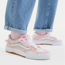 Pink and white sneakers worn with light blue jeans on a white background