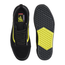 Black Vans slip-on sneakers shown from the top and bottom, featuring a bright neon yellow accent on the side, laces, and outsole.