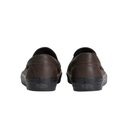 A pair of dark brown leather slip-on shoes shown from the back, featuring dark brown stitching and black rubber soles with a subtle Vans logo on the heel.