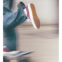 Person wearing a pink sneaker with a white sole on a blurred background