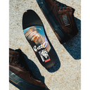 Three Vans Old Skool sneakers in dark brown suede and black canvas are arranged on a textured concrete surface with sharp shadows. The center shoe is turned upside down to show the insole, which features a colorful graphic of a swirling orange and blue vortex with the white Vans logo and 'OLD SKOOL' text.