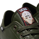 Close-up of a green Vans sneaker featuring a hockey-themed tongue patch with a hockey mask graphic and the Vans logo.