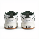 A pair of Vans One True Way sneakers shown from the back, featuring a white leather upper, dark green lining, a white heel tab with 'Una' written on it, and a brown gum sole.