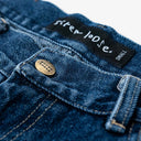 Close-up of blue denim jeans with 'sister loose' label and button.