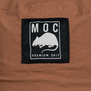 Close-up of a label with 'MOC' and a graphic on brown fabric